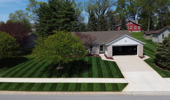 Dark green, striped lawn with home