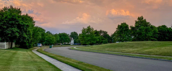 Photograph of a striped green lawn in a neighborhood at sunset