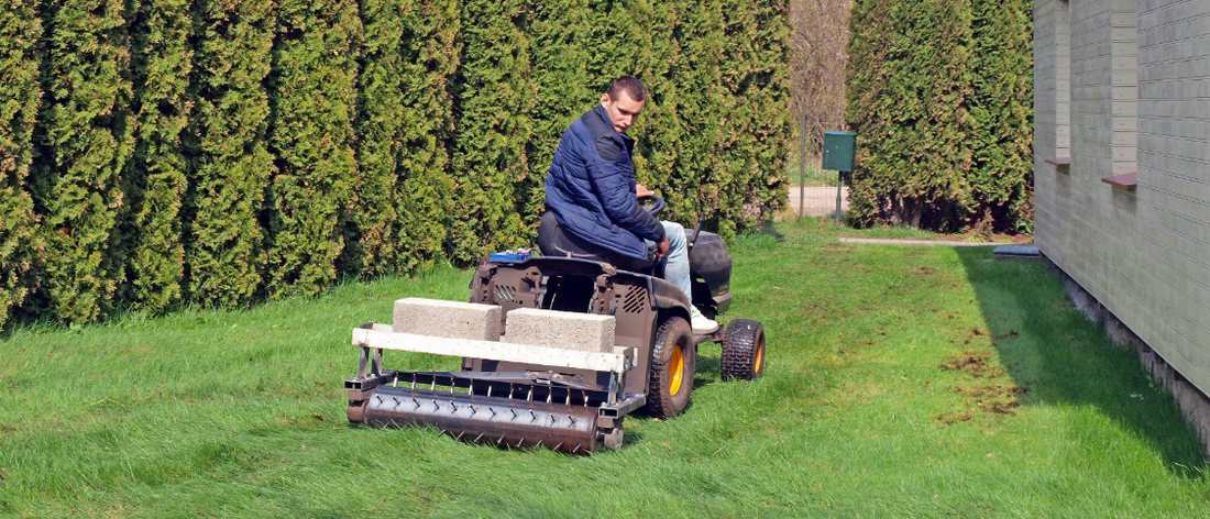 Man using a core aeration machine to aerate lawn