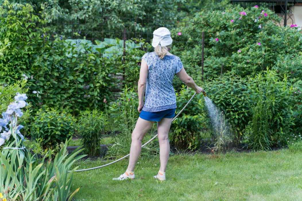 woman watering her bahia grass