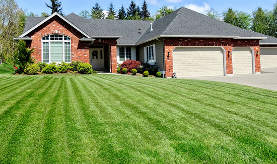 front yard with green striped lawn in front of a brick house