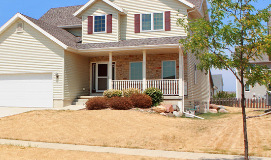 Two-story home with a pale brown/yellow front lawn
