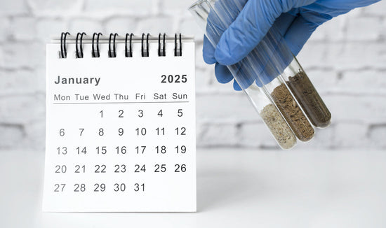 Desk calendar showing the month of January 2025, with a gloved hand holding vials of soil to illustrate the importance of soil testing in January