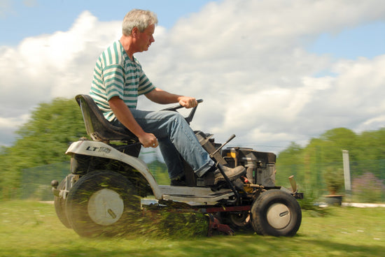 man mowing lawn on sit down lawn mower