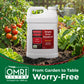 A large white plastic jug of Simple Grow Solutions Root-Humus liquid fertilizer stands in a garden bed with tomato plants, basil, and soil. A green banner at the bottom reads &